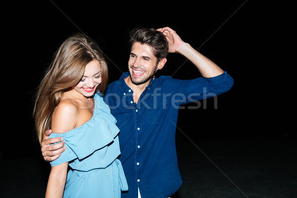 Happy couple standing and embracing at night on the beach Stock photo © deandrobot