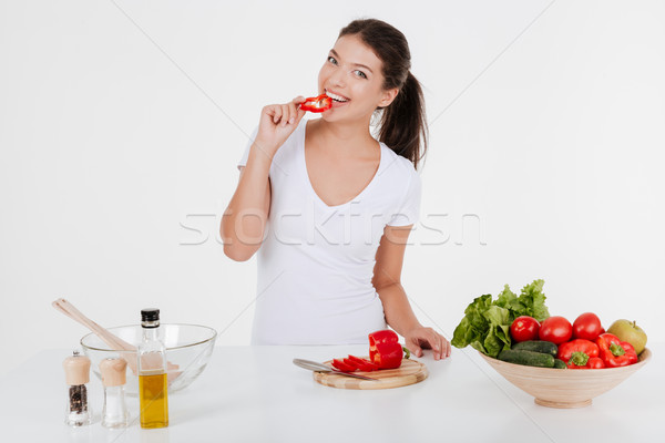 Happy young lady cooking with vegetables while eating them Stock photo © deandrobot