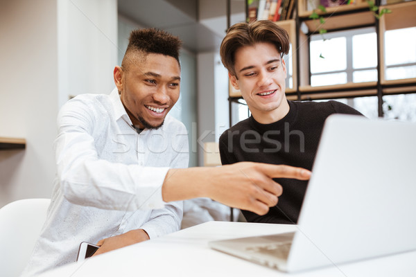 Foto stock: Dos · jóvenes · estudiantes · sesión · biblioteca · usando · la · computadora · portátil