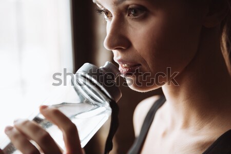 Cropped picture of gorgeous young fitness woman drinking water. Stock photo © deandrobot