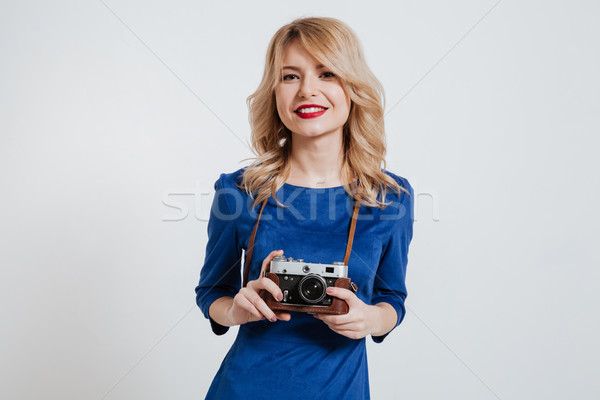 Cheerful young lady holding camera over white background. Stock photo © deandrobot