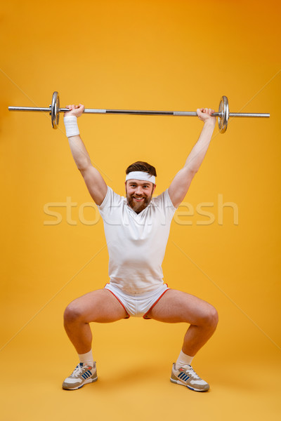 Full length of athletic man doing squatting exercises with barbell Stock photo © deandrobot