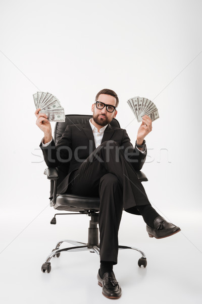 Businessman sitting on chair holding money. Stock photo © deandrobot