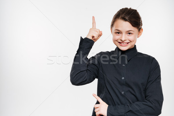 Smiling young girl posing and pointing Stock photo © deandrobot
