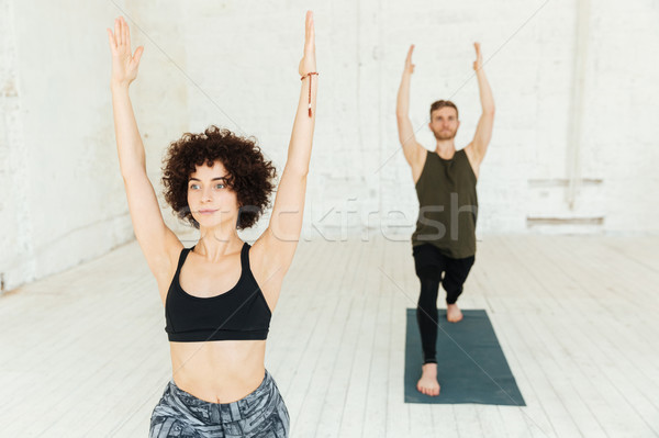 Young woman with curly hair raising her hands while making exercise Stock photo © deandrobot