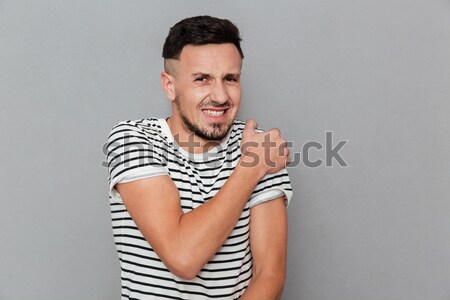 Retrato jóvenes casual hombre dolor en el hombro aislado Foto stock © deandrobot