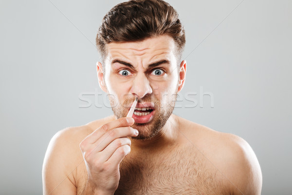 Horizontal picture of scared man removing nose hair with tweezer Stock photo © deandrobot
