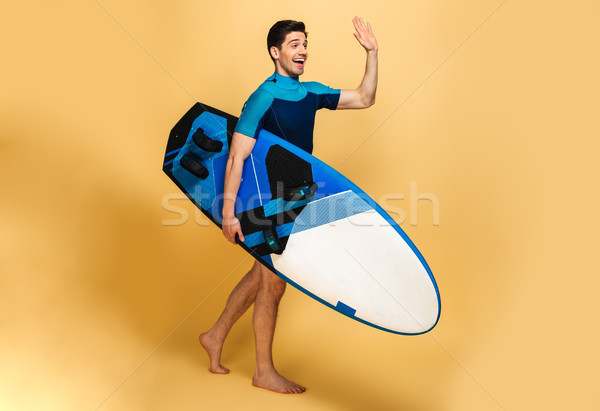 Excited young man dressed in swimsuit looking aside waving. Stock photo © deandrobot