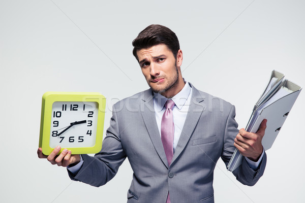 Unhappy businessman holding folders and clock Stock photo © deandrobot