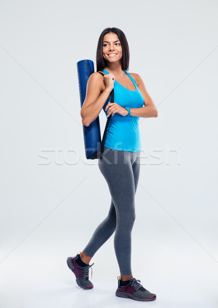 Smiling sports woman with yoga mat walking Stock photo © deandrobot