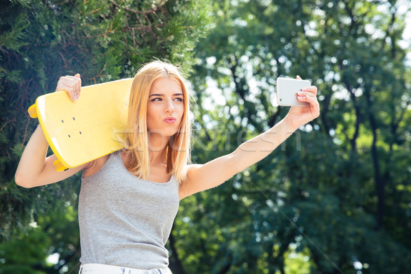 Girl with skateboard making selfie photo on smartphone Stock photo © deandrobot