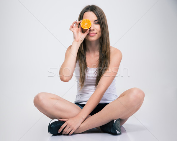 Girl sitting on the floor and covering one eye with orange Stock photo © deandrobot