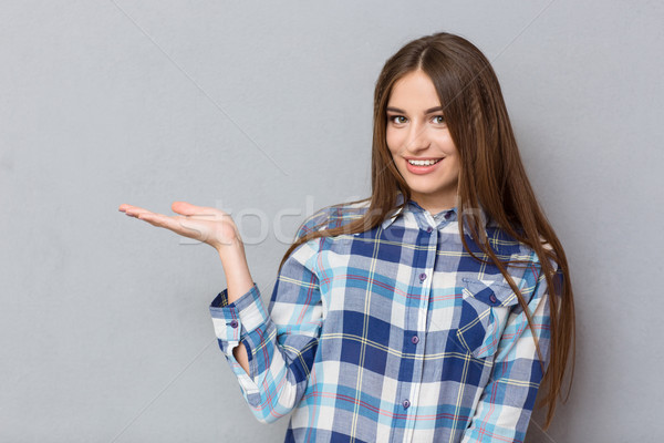 Smiling woman holding copyspace on the palm Stock photo © deandrobot