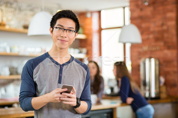 Yakışıklı Asya adam ayakta kafe cep telefonu Stok fotoğraf © deandrobot