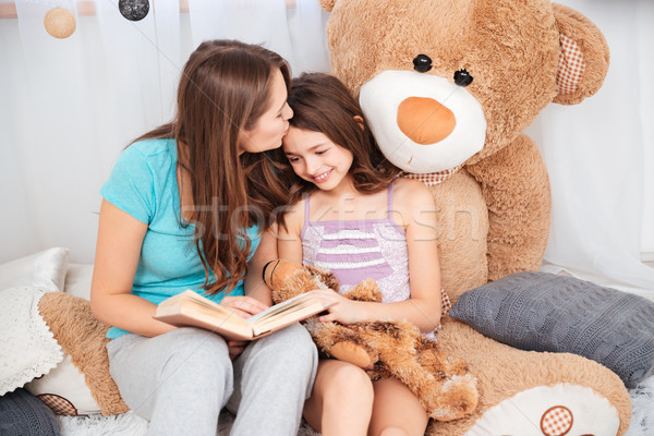 Two cute smiling sisters reading and kissing  Stock photo © deandrobot