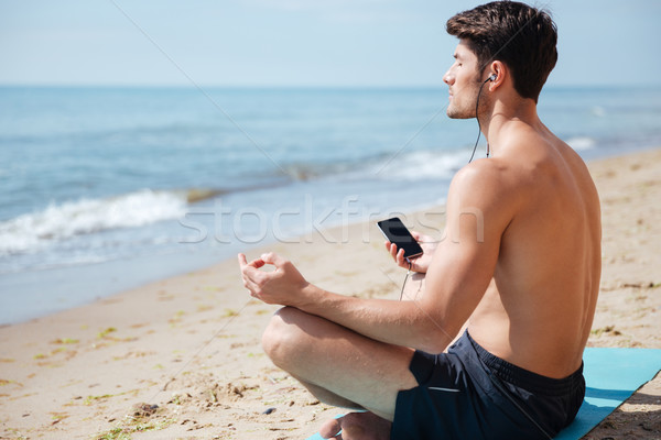 Stockfoto: Man · mediteren · luisteren · naar · muziek · smartphone · strand · knap