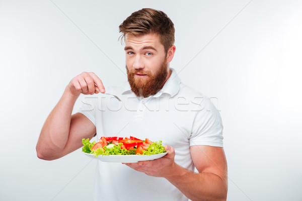 Young man holding fork to eat fresh vegetable salad meal Stock photo © deandrobot