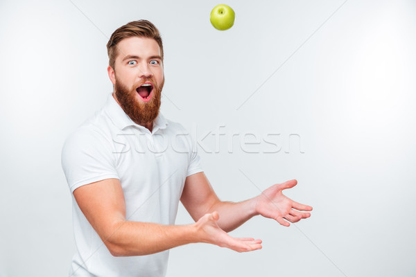Portrait of handsome funnny bearded man throwing apple up Stock photo © deandrobot