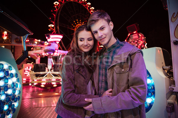 Smiling beautiful young couple standing togetehr in amusement park Stock photo © deandrobot
