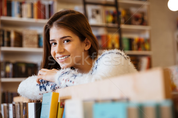Mosolyog fiatal nő dől könyvespolc könyvtár közelkép Stock fotó © deandrobot