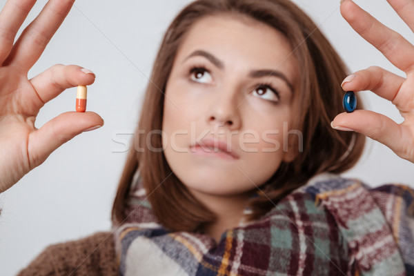 Thoughtful sick young lady choosing medicine pills Stock photo © deandrobot