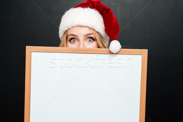 Woman in santa hat hiding face behind blank white board Stock photo © deandrobot