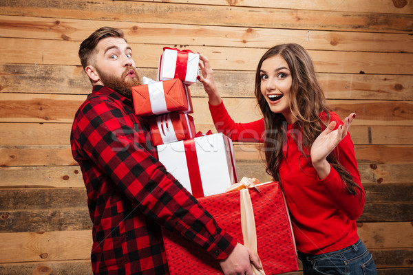 Cheerful happy couple standing with heap of xmas present boxes Stock photo © deandrobot