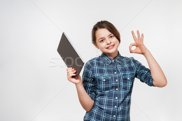 Cheerful young girl using tablet computer make okay gesture Stock photo © deandrobot