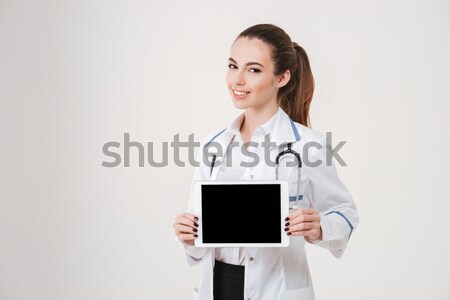 Confident young female nurse or doctor in white coat Stock photo © deandrobot