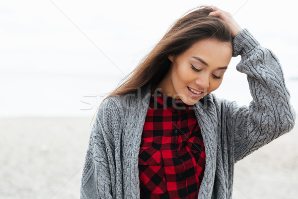 Positive woman looking down while walking on beach Stock photo © deandrobot