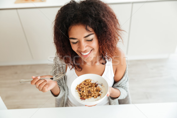 Young happy woman eating breakfast in kitchen Stock photo © deandrobot