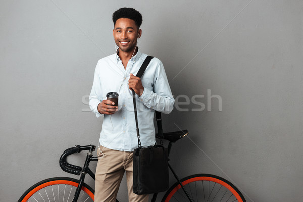 Happy man standing near bicycle isolated listening music drinking coffee. Stock photo © deandrobot
