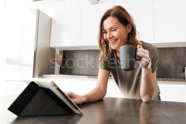 Happy Casual woman drinking coffee and using tablet computer Stock photo © deandrobot