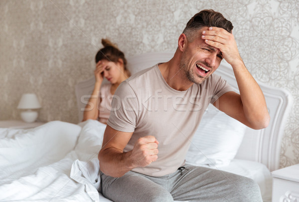 Confused worried man sitting on bed with his girlfriend Stock photo © deandrobot