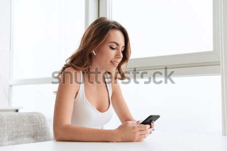 Cheerful young lady listening music with earphones Stock photo © deandrobot