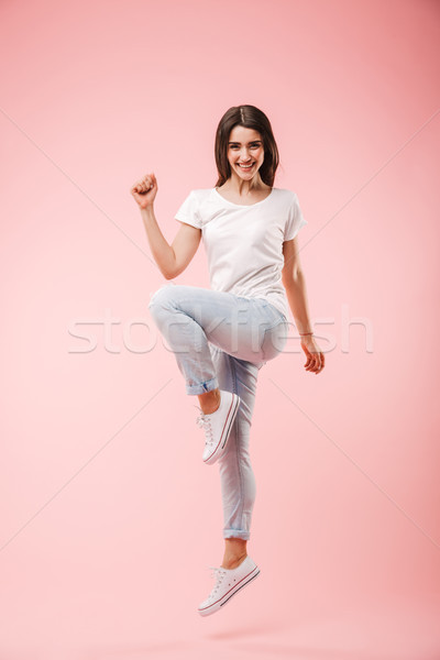 Full length of an excited young woman jumping Stock photo © deandrobot