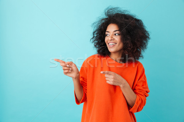 Photo of pleased woman in red shirt looking aside and pointing f Stock photo © deandrobot