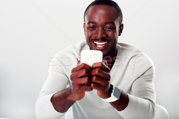 Portrait of a laughing african man using smartphone Stock photo © deandrobot