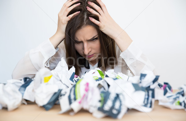Portrait Of frustrated businesswoman sitting at the table with trash papers Stock photo © deandrobot