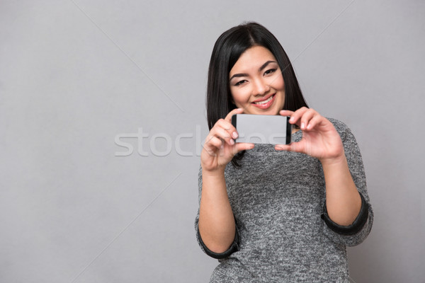 Asian girl taking photos using cellphone Stock photo © deandrobot