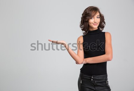 Smiling beautiful woman hoding copyspace on the palm over background Stock photo © deandrobot