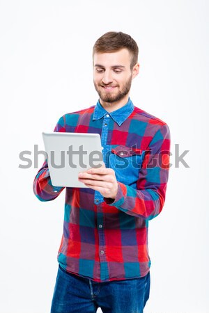 Content smiling attractive man in plaid shirt using tablet computer Stock photo © deandrobot