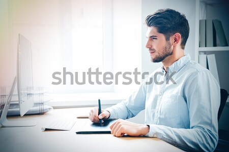 Concentrated designer drawing using computer and graphic tablet Stock photo © deandrobot