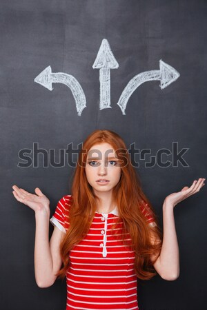 Back view of woman choosing direction over chalkboard background Stock photo © deandrobot