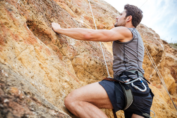 Jeune homme escalade raide mur montagne jeunes [[stock_photo]] © deandrobot