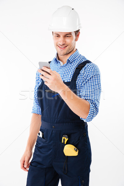Portrait of a handsome builder standing and using mobile phone Stock photo © deandrobot