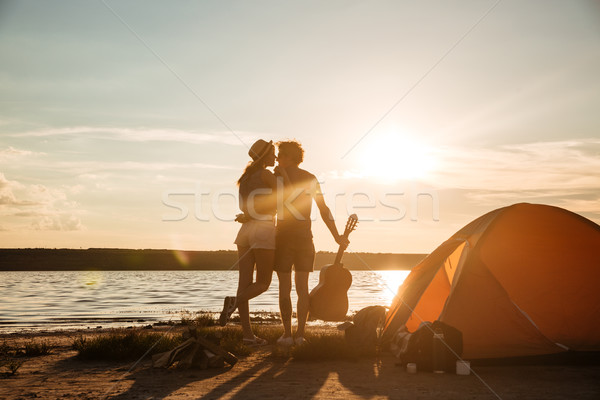 Back view of couple with guitar hugging on the sunset Stock photo © deandrobot