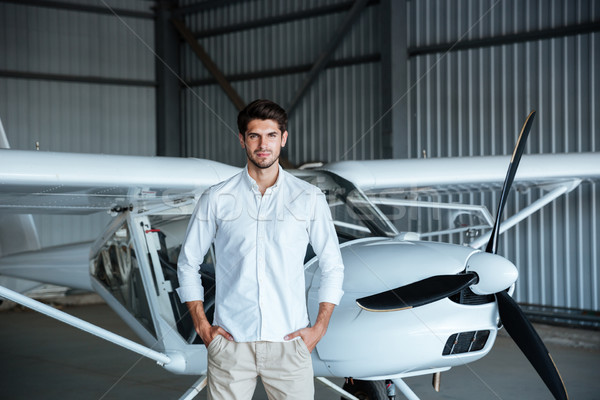 Confident man standing in front of small aircraft Stock photo © deandrobot