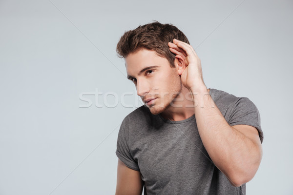 Curious handsome young man in plaid shirt overhearing rumors Stock photo © deandrobot