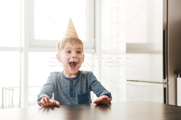 Little happy birthday boy sitting in kitchen while screaming Stock photo © deandrobot